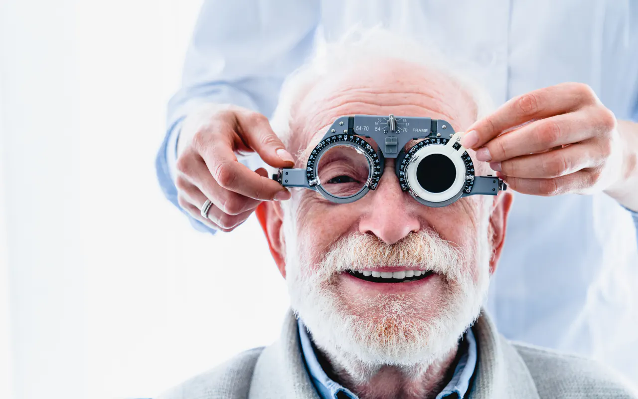 Basse vision : monture d’essai ajustée devant les yeux d’un patient âgé souriant