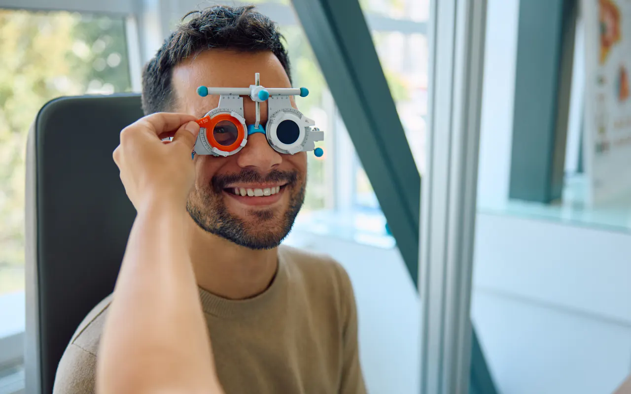 Examen de la vue chez l’optométriste : monture d’essai posée devant les yeux d’un patient souriant