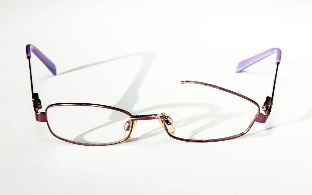 Lunettes cassées : monture en métal violet dont un verre est sorti du cerclage