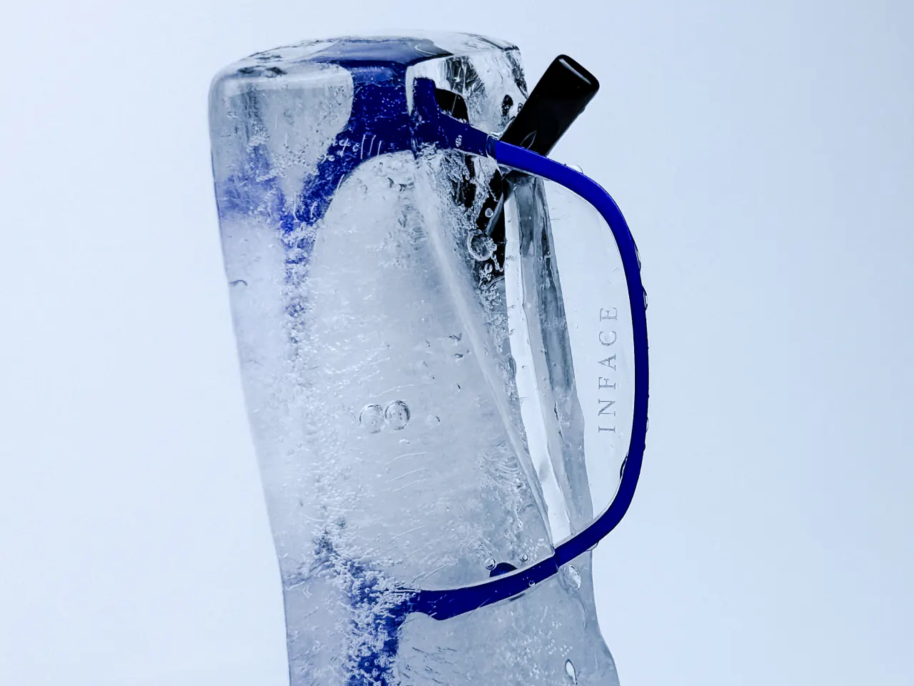 Monture Inface bleue prise dans un bloc de glace, sur un fond bleu très clair