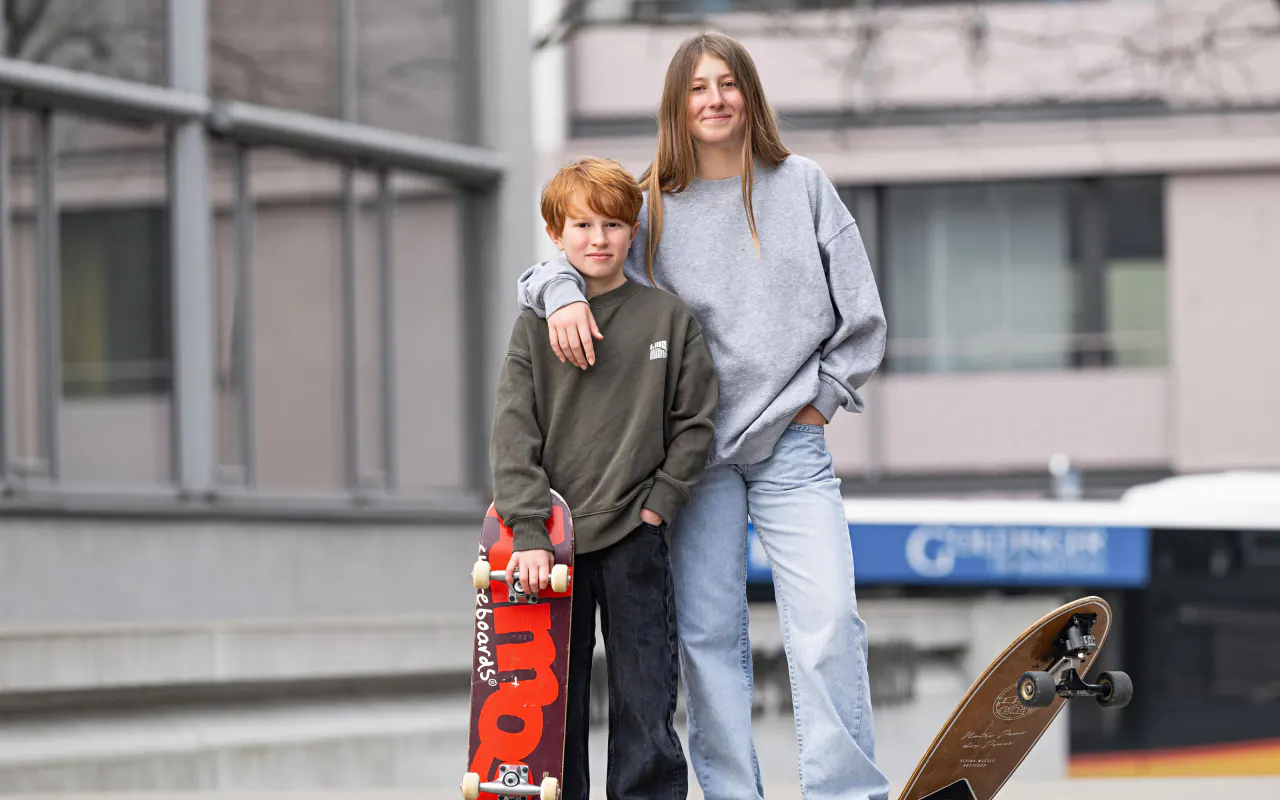 Prévention de la myopie chez les jeunes : un garçon et une adolescente sans lunettes, dehors avec leurs skateboards